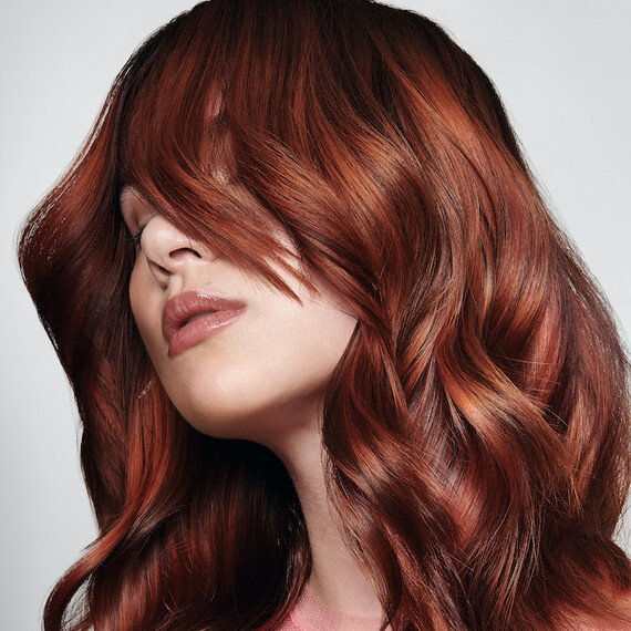 Model with long, glossy, copper hair featuring a golden glass glow.