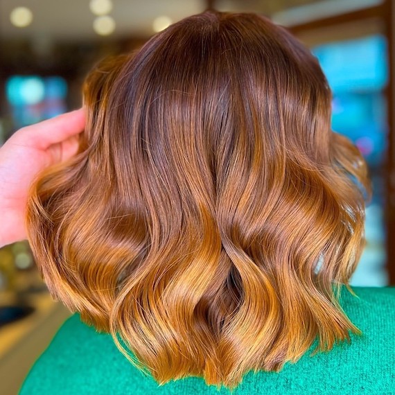 Back of model’s head with shoulder-length hair that’s dark brown on the roots and a light copper shade through the lengths.