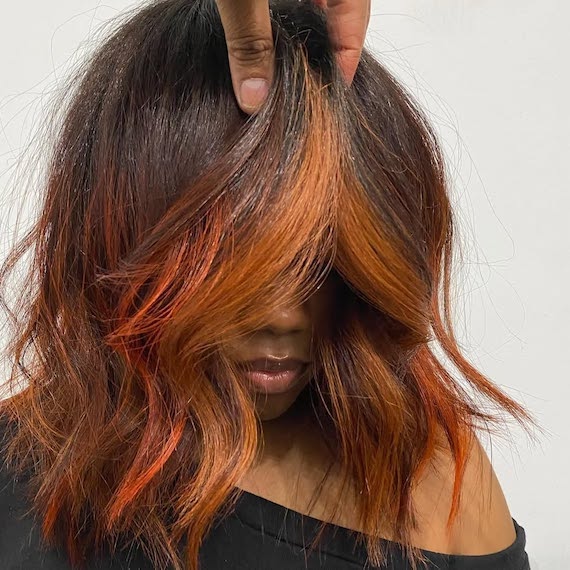 Model with dark brown hair featuring chilli red and copper highlights through the lengths and ends.