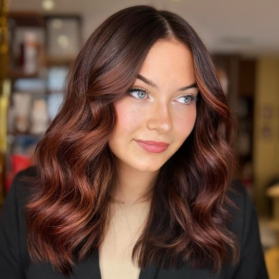 Model with dark brown hair featuring very subtle copper brown balayage.