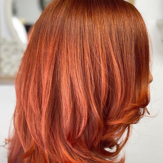 Side profile of woman with mid-length, copper red hair color, created using Wella Professionals.