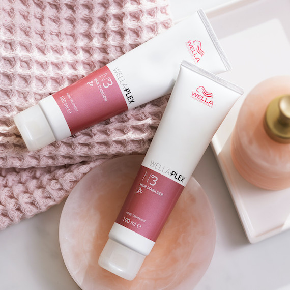 Zwei Tuben WellaPlex N°3 Hair Stabilizer von Wella Professionals liegen auf einem Handtuch und einer Seifenschale.