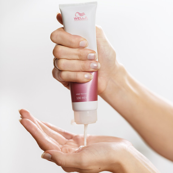 Nahaufnahme einer Hand, die eine Tube WellaPlex N°3 Hair Stabilizer hält und das Produkt in die andere Handfläche gibt.