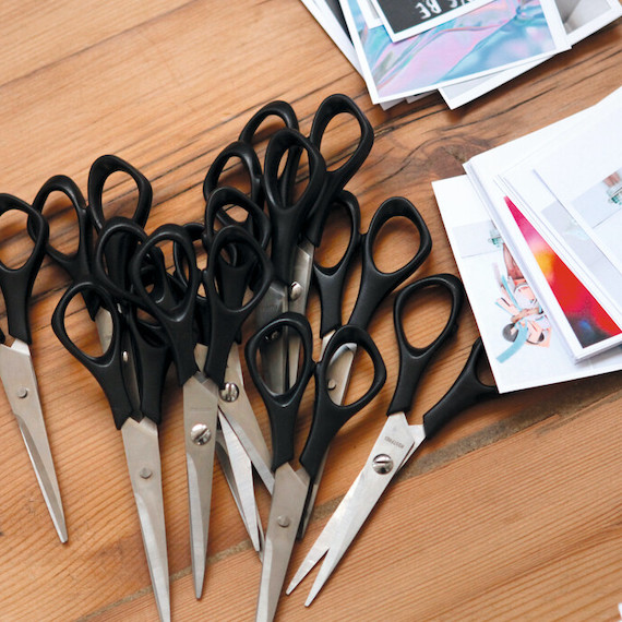 Pile of black handle scissors next to stacks of cut-out pictures