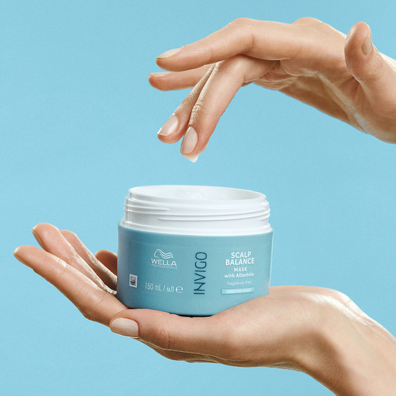 Hands hold a jar of INVIGO Scalp Balance Mask.