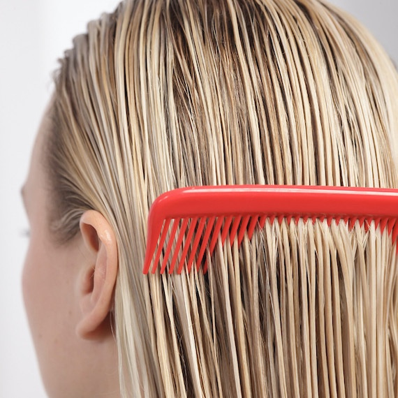A red comb glides through blonde, towel-dried hair.