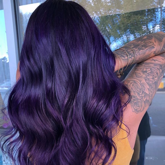 Back of woman’s head with long, wavy, dark purple hair, created using Wella Professionals.