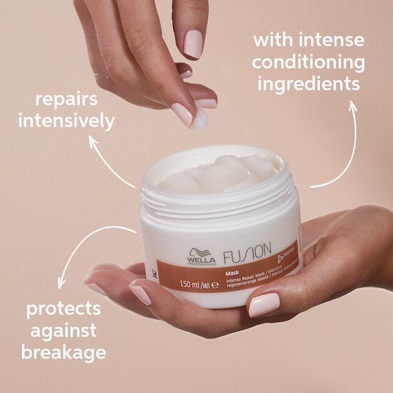 One hand holds a tub of Wella Fusion Intense Repair Mask with the lid off.