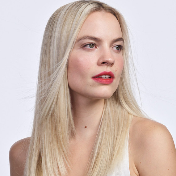 Headshot of a model looking into the distance with straight platinum blonde hair and red lips