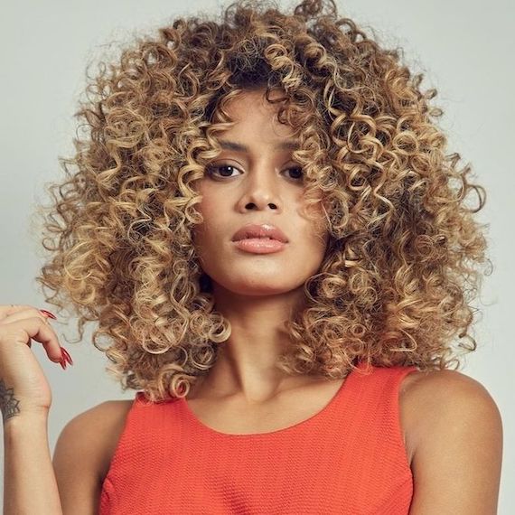 Model with golden blonde curly hair faces the camera.
