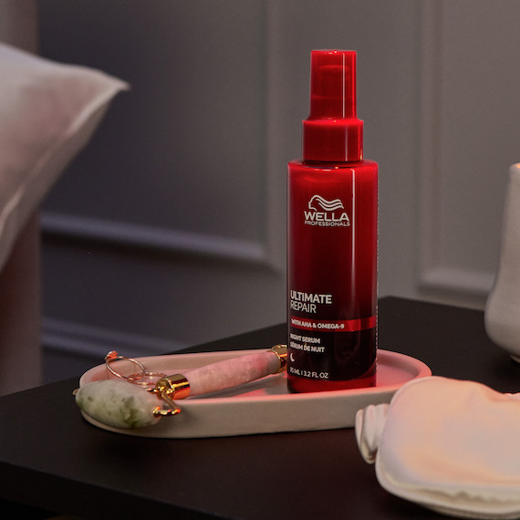 ULTIMATE REPAIR Night Serum bottle on a nightstand next to a jade roller.