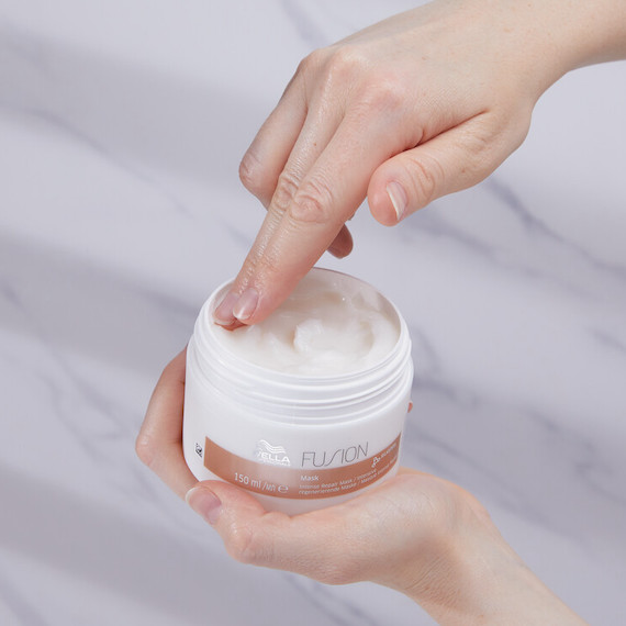 Hand dipping into a pot of Fusion Intense Repair Mask.