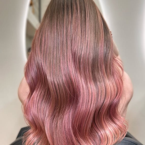 Model with dark blonde hair and a dusty pink balayage.