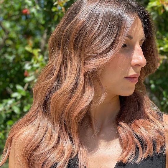 Model with dark brown hair and pinky-peach tones painted through the lengths.