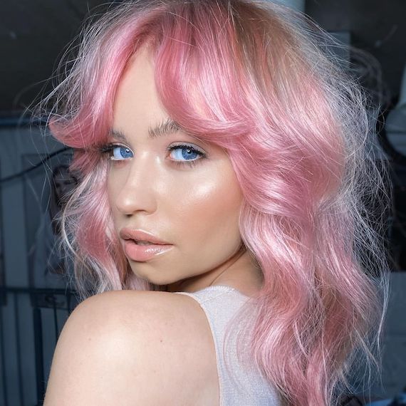 Model with tousled, pink hair and grown-out bangs.