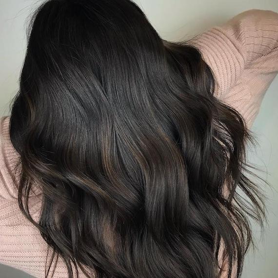 Back of woman’s head with dark espresso brown hair and coffee highlights.