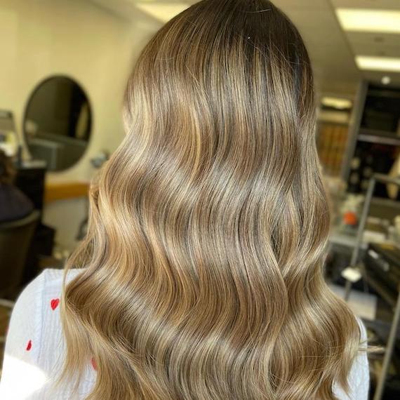 Back of model’s head with wavy hair featuring beige blonde highlights.
