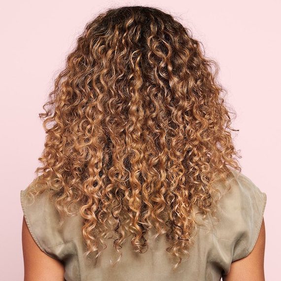 Back of model’s head with long, curly, golden blonde hair.