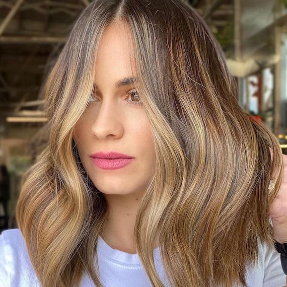 Model faces the camera with blow-dried, toffee blonde hair.