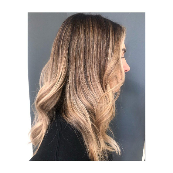 Seitenansicht einer Frau mit langer, blonden Balayage und Money Piece Hair