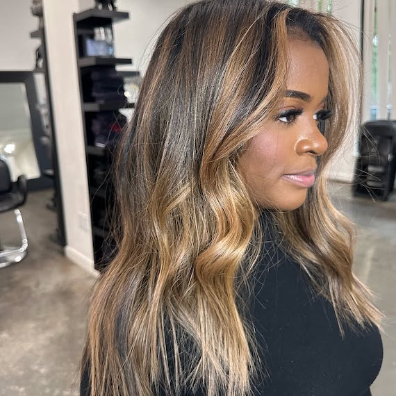 Warm caramel balayage on long dark hair.