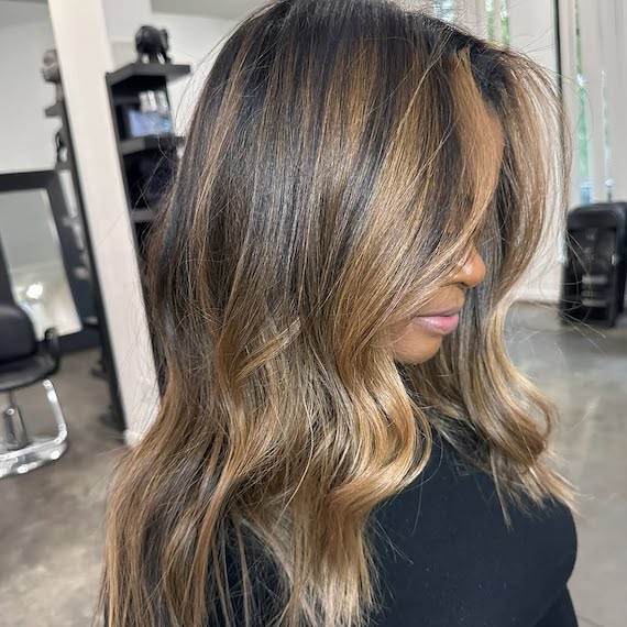 Warm caramel balayage on long dark hair.