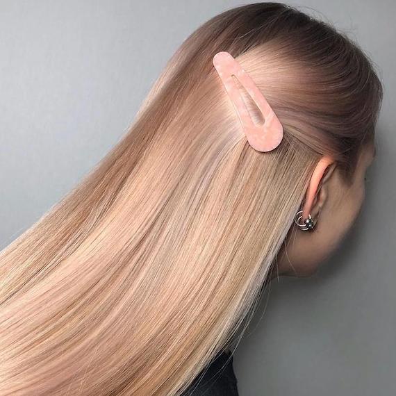 Side profile of woman with long blush blonde hair clipped back with a pink grip.