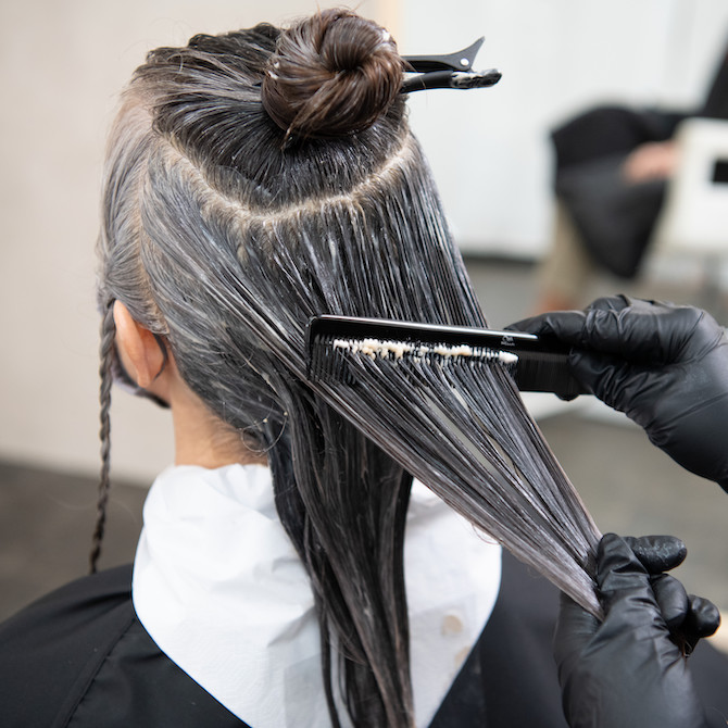 Back of model’s head. Wella Color Touch is being distributed through her hair with a comb.