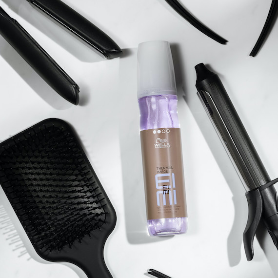 Wella’s EIMI Thermal Image is surrounded by heated hair tools and a hairbrush. 