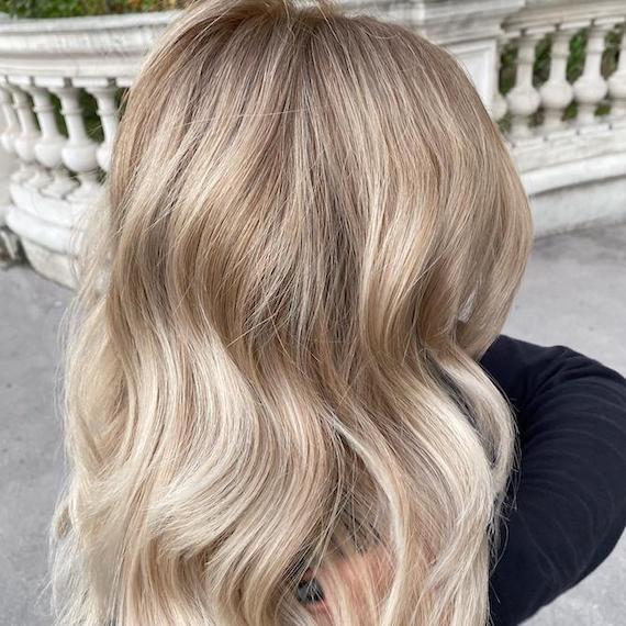 Back of woman’s head with wavy hair and ivory blonde foilyage, created using Wella Professionals.