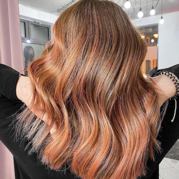 Back of woman’s head with mid-length, wavy hair and apricot foilyage, created using Wella Professionals.