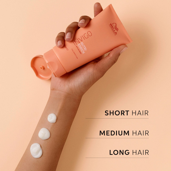 Hand holds up a tube of INVIGO Nutri-Enrich Frizz Control Cream.