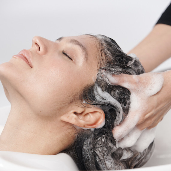 Model’s hair is washed by a hairdresser.