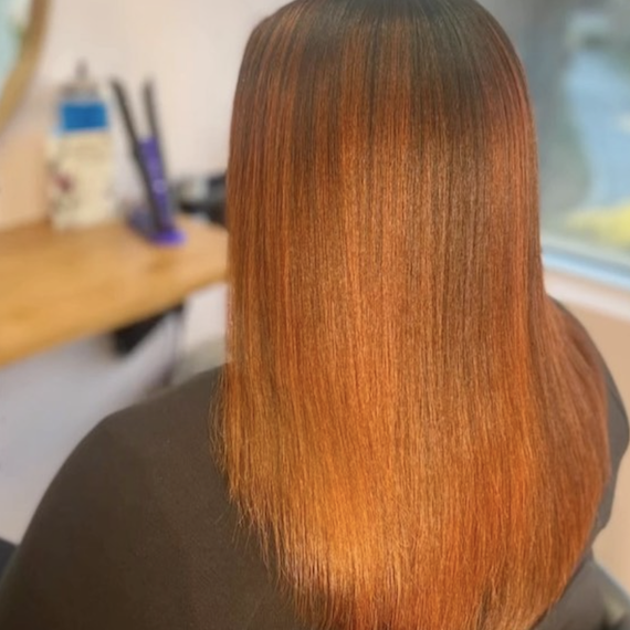 A person with long straight ginger brown hair faces away from the camera 