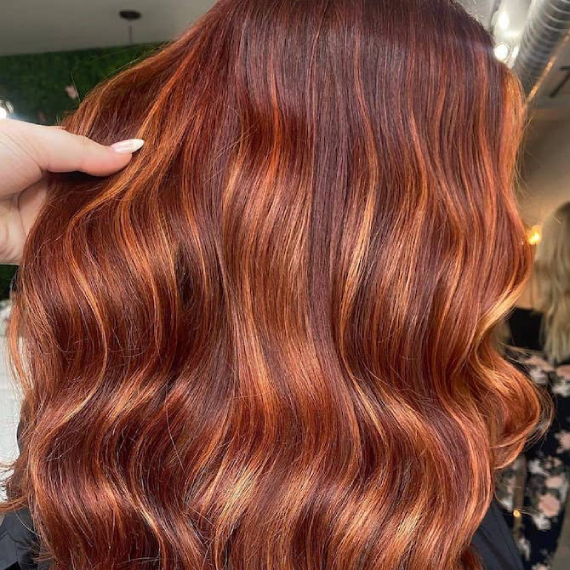 Long, wavy dark ginger brown hair with caramel highlights