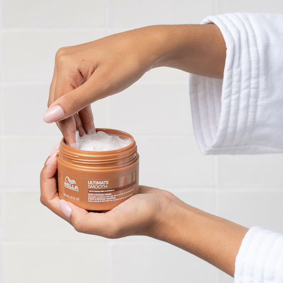Model scoops ULTIMATE SMOOTH Mask out of the jar.