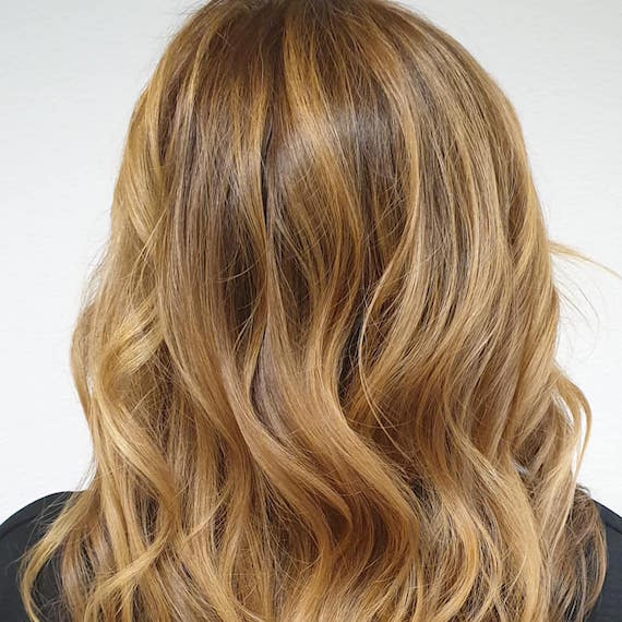 Back of woman’s head with medium-length, medium golden blonde hair, created using Wella Professionals. 