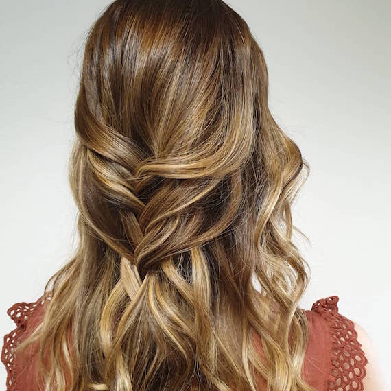 Back of woman’s head with dark golden blonde hair in a half-up braid, created using Wella Professionals. 