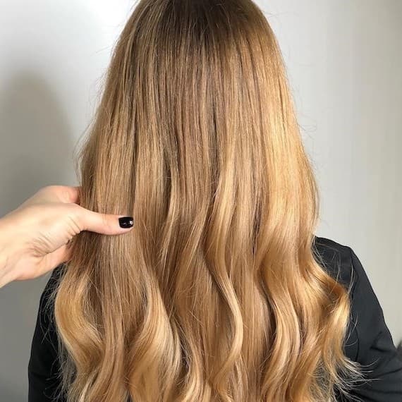 Back of woman’s head with long, wavy, pure golden blonde hair, created using Wella Professionals.