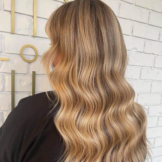 Back of woman’s head with long, beachy hair and golden blonde highlights, created using Wella Professionals.