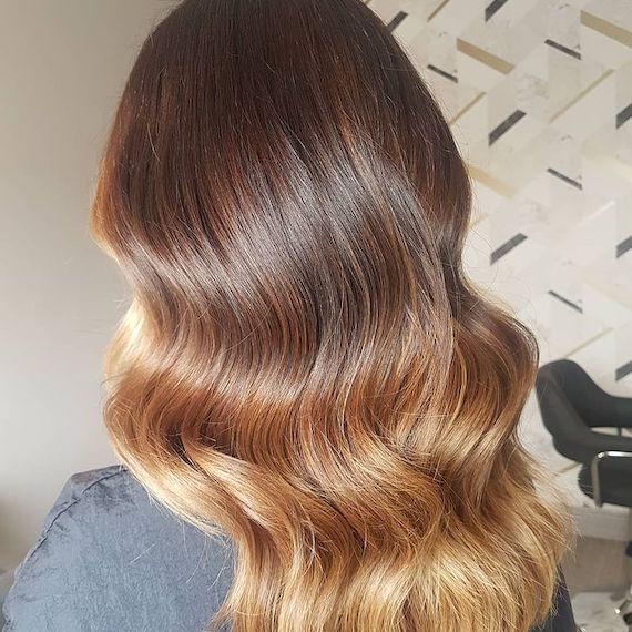Back of woman’s head with long wavy, golden blonde ombre hair, created using Wella Professionals.
