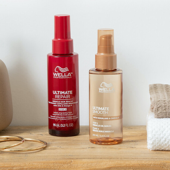 ULTIMATE REPAIR Miracle Hair Rescue and ULTIMATE SMOOTH Miracle Oil Serum side by side on a wooden surface.