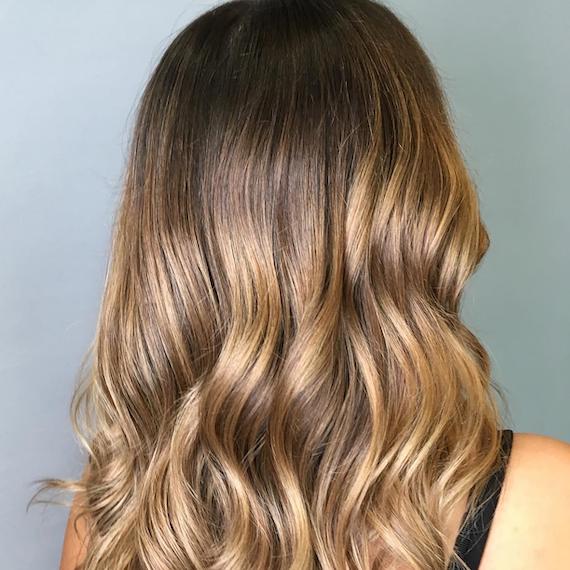 Image of the back of a woman’s head with golden brown ombre.