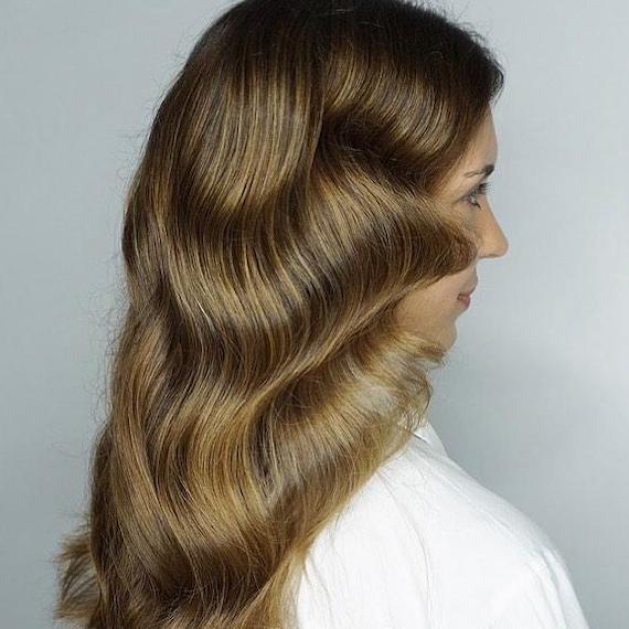 Side profile of woman with medium golden brown hair, created using Wella Professionals.