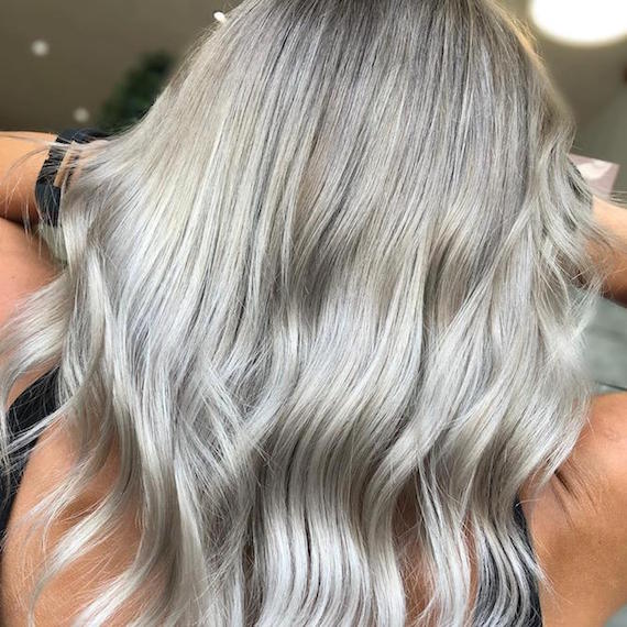 Back of woman’s head with long, wavy, gray blonde hair, created using Wella Professionals.