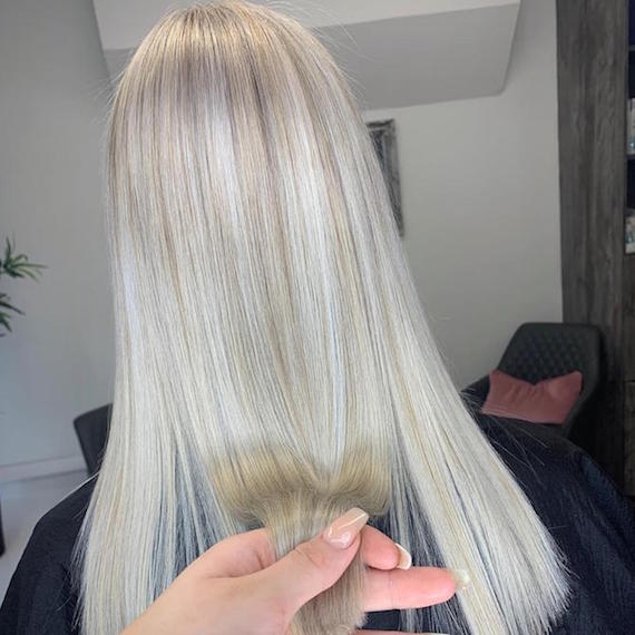 Back of woman’s head with long, straight, gray blonde highlights, created using Wella Professionals.