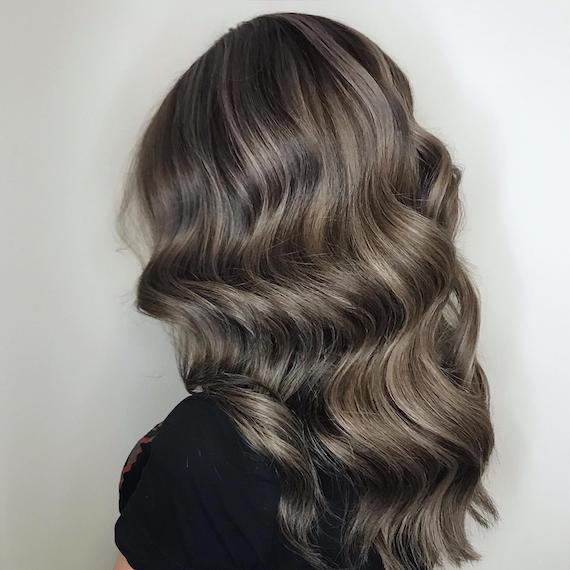 Back of woman’s head with dark brown hair and gray highlights, created using Wella Profes-sionals.