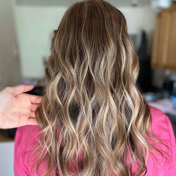 Back of woman’s head with long, wavy hair after gray roots have been colored, created using Wella Professionals. 