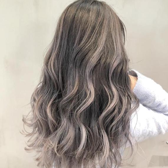 Back of woman’s head with long, wavy, salt ‘n’ pepper colored hair.