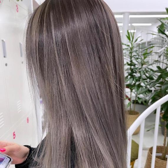 Side profile of woman with long, straight, dark gray hair, created using Wella Professionals.